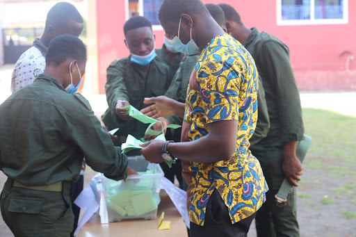 Staff acting as election officials to count ballots after close of polls, while the school cadet watch on as security