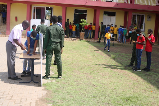 Staff acting as election officials to count ballots after close of polls, while the school cadet watch on as security